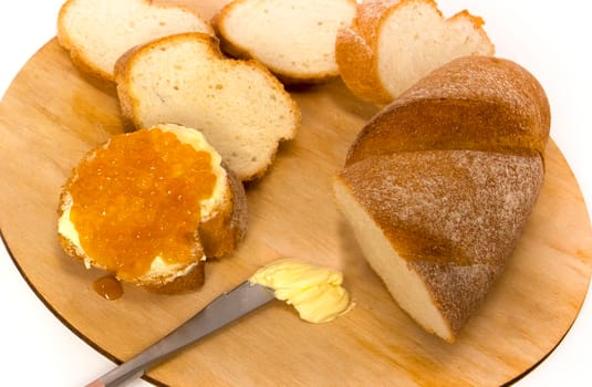 Fresh baguettes with crispy crust with butter chopped on a cutting board on a white table. Tasty breakfast. kitchen knife. High quality photo