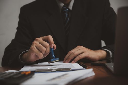 Man stamping approval of work finance banking or investment marketing documents on desk.