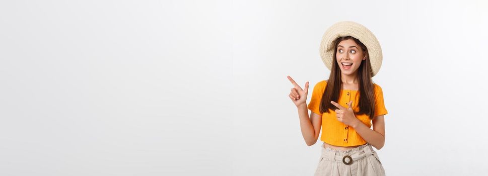 Teenager girl on summer vacation surprised and pointing finger on copy space over isolated white background