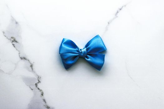 Happy holidays, festive decoration and brand sale promotion concept - Blue silk ribbon and bow on luxury marble background, holiday flatlay backdrop