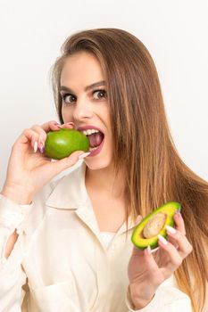 Diet nutrition. Beautiful young caucasian woman biting organic green avocado on white background. Healthy lifestyle, health concept