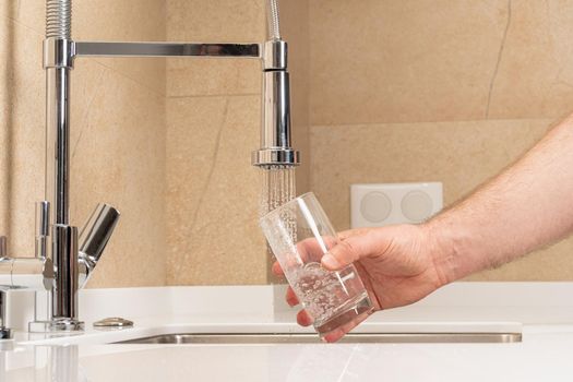 man picking up a glass of drinking water in the kitchen.