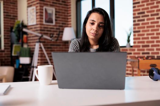 Business woman doing remote online job at home, using laptop to send email and analyze research information. Working on internet report with startup network or attending school class lesson.