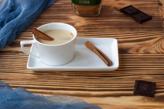a cup with cappuccino stands on a saucer, on a wooden background. fresh frothy coffee, cinnamon roll. High quality photo