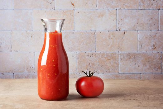 Glass bottle with homemade tomato sauce and ripe tomato on the table. Selective focus. Place for text.