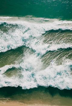 Beach and waves from above. water background from the top. Summer attacks from the air. Aerial view of a blue ocean.