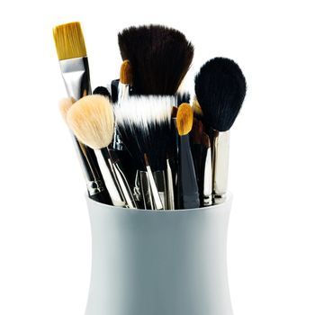 Tools of the beauty trade. A set of makeup brushes in their container, isolated on white