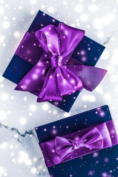 Branding, glamour and cold season concept - Winter holiday gift box with purple silk bow, snow glitter on marble background as Christmas and New Years presents for luxury beauty brand, flatlay design