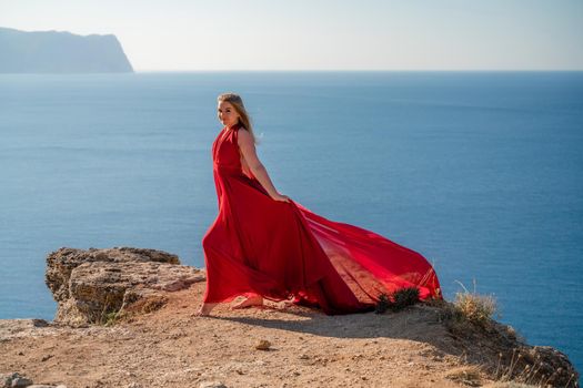 A woman in a red flying dress fluttering in the wind, against the backdrop of the sea