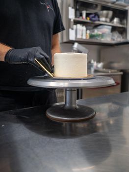 Decorator using spatula and scraper to smooth buttercream on a frosted cake