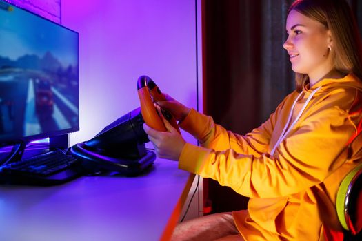 girl gamer playing racing on a computer. She uses a steering wheel. emotional play