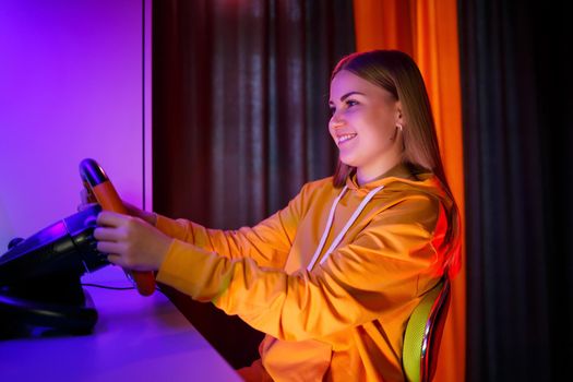 girl gamer playing racing on a computer. She uses a steering wheel. emotional play