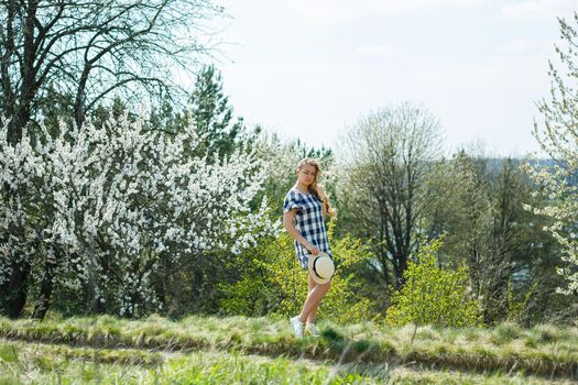 beautiful girl in a dress walking in the spring forest where the trees bloom