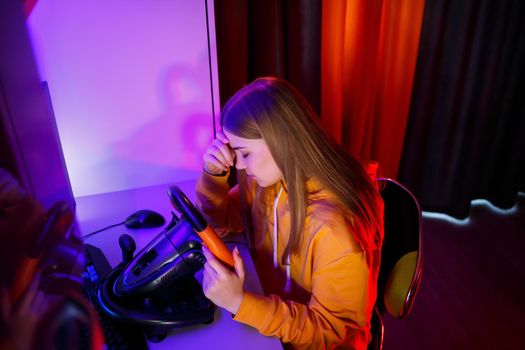 girl gamer playing racing on a computer. She uses a steering wheel. emotional play
