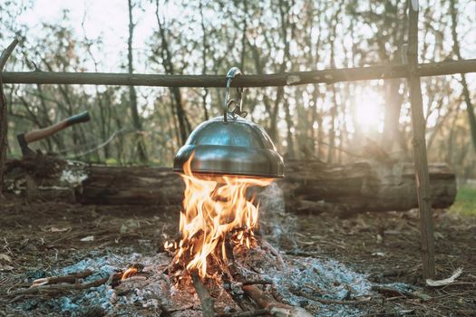 Kettle is heated on a bright bonfire. Wonderful evening atmospheric background of campfire. travel in the forest. download photo