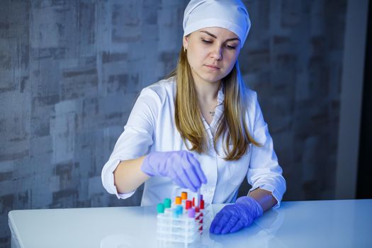 A medical professional, laboratory assistant, doctor performs an analysis in a laboratory, uses test tubes, a pipette and a petri dish for the presence of bacteria in the human body. Selective focus