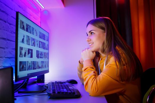 Girl freelancer looks on a computer screen at a cat. Sitting in an apartment at a computer desk