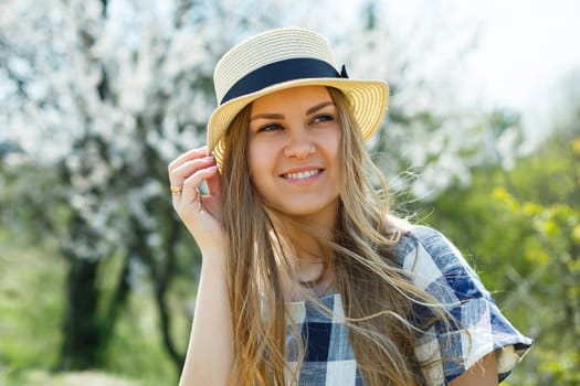 A girl with a beautiful spring smile against a flowering tree