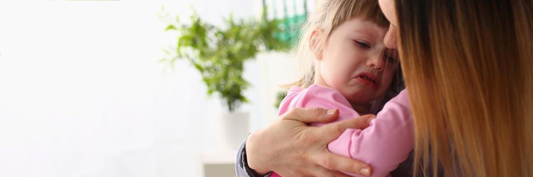 Mother consoles crying baby girl. Parenthood and family support concept