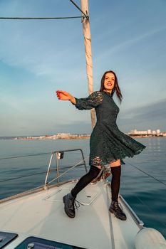 Woman standing on the nose of the yacht at a sunny summer day, breeze developing hair, beautiful sea on background.