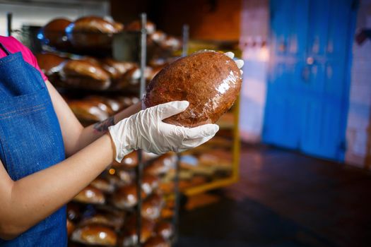 Girl baker works in a bakery. Fresh crispy bread close up