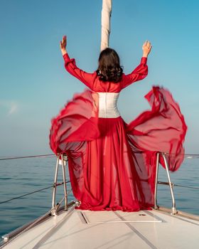 Attractive middle-aged woman in a red dress on a yacht on a summer day. Luxury summer adventure, outdoor activities