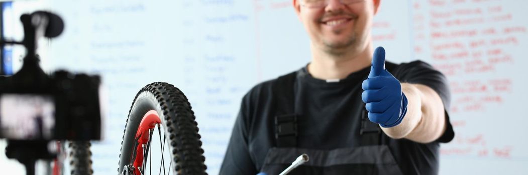 Bicycle repairman in workshop holding thumbs up. Quality bike repair concept