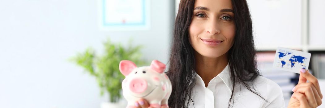 Smiling woman holding piggy bank and bank card. Card with cashback for purchases concept