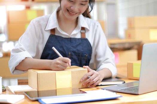 Successful Asian women entrepreneur with parcel boxes in her own job shopping online business at home office. start up small business, sme concept..