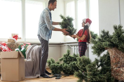 Father and daughter assembling christmas tree, smiling - christmas, holiday, winter concept, family activity