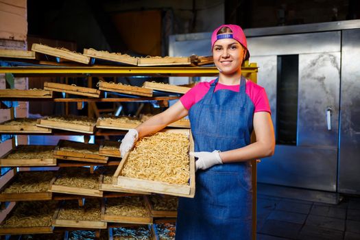 Make the noodles. Pasta factory. Spaghetti production. Raw pasta. Worker with a box of pasta. Girl works in the production of pasta