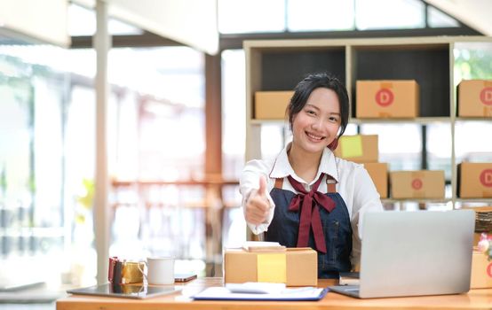 Portrait young attractive asia female owner startup business look at camera work happy with box at home prepare parcel delivery in sme supply chain, procurement, omnichannel commerce online concept..