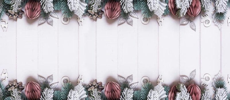 Christmas banner with flat lay snow pine trees, paper and wooden Christmas toys on wooden background.