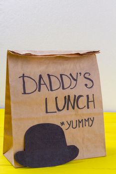 Paper bag with yummy daddys lunch with hat. Fathers day concept.