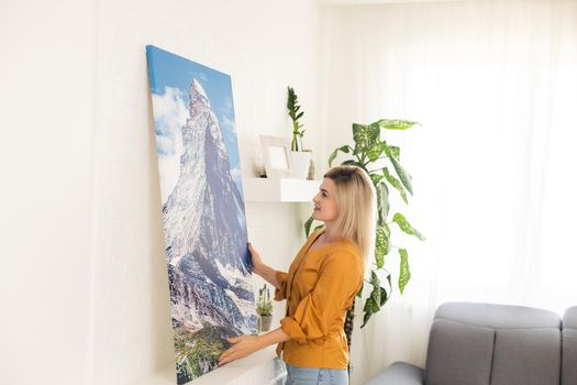 Woman hanging a photo canvas on a wall