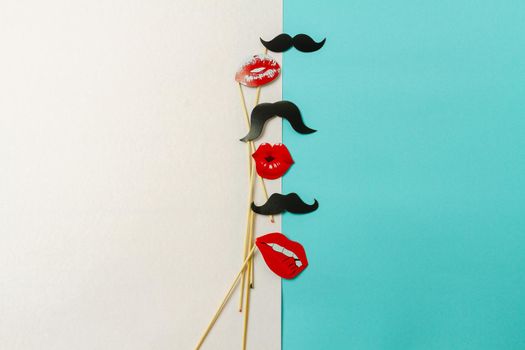 Top view sticks with moustaches and lips. Contrast on mens and womens. White and turquoise background.