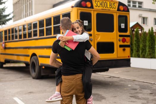 first day at school. father leads a little child school girl in first grade