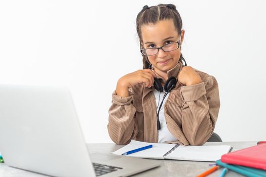 Smiling little Caucasian girl in headphones handwrite study online using laptop at home, cute happy small child in earphones take Internet web lesson or class on computer, homeschooling concept.