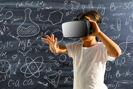 Girl with virtual reality glasses in classroom. Concept of school and modern technology.