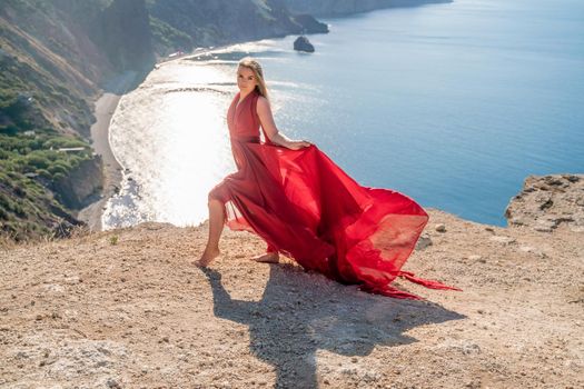 A woman in a red flying dress fluttering in the wind, against the backdrop of the sea