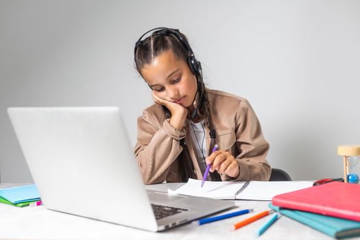 Tired schooler child girl at home with laptop for remote connection with her classmates and the teacher - Bored little girl learning using internet lessons during coronavirus outbreak