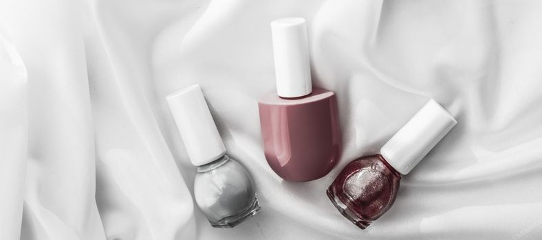 Cosmetic branding, salon and glamour concept - Nail polish bottles on silk background, french manicure products and nailpolish make-up cosmetics for luxury beauty brand and holiday flatlay art design