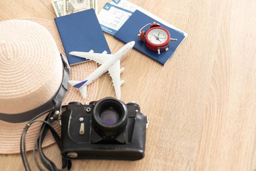 Preparation for Traveling concept, camera, tickets, money, passport, airplane on a vintage wooden background with copy space