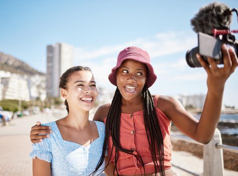 Influencer woman friends on beach live streaming beach holiday or vacation for social media in city, summer and blue sky. Gen z girl couple or people in selfie portrait or outdoor podcast near ocean.