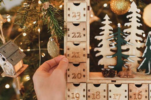 Hand opens wooden advent calendar