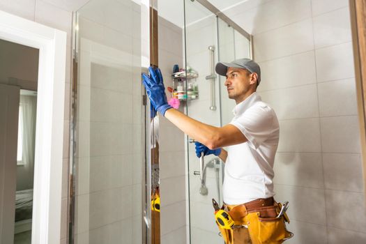 Plumber installing shower stall, work in bathroom