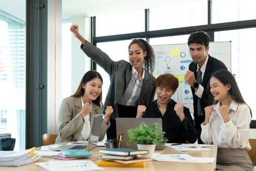 Portrait success and team work concept. Group of business partners with raised up hands in light modern workstation, celebrating the breakthrough in their company.