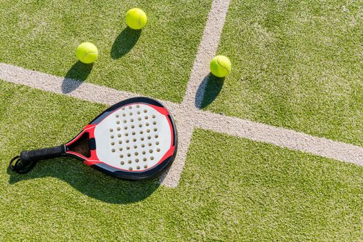 top view of a paddle tennis racket and balls on court of artificial grass, indoor sports concept and sporty lifestyle