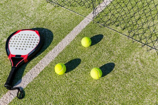 paddle tennis racket, balls and net on court of artificial turf, indoor sports concept and sporty lifestyle