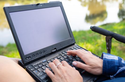 The girl sits in a chair near the autumn lake and works on a laptop freelance camping. Robot out of the office, phoned with colleagues